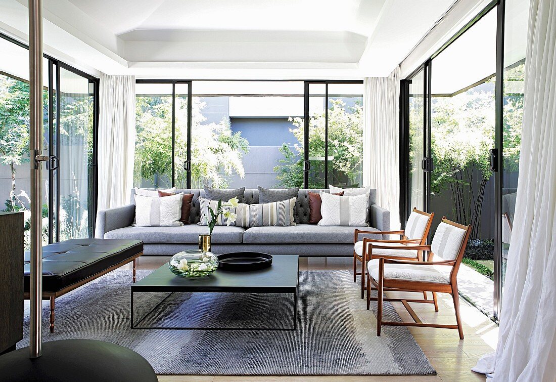 Living room with glass walls leading to summery garden