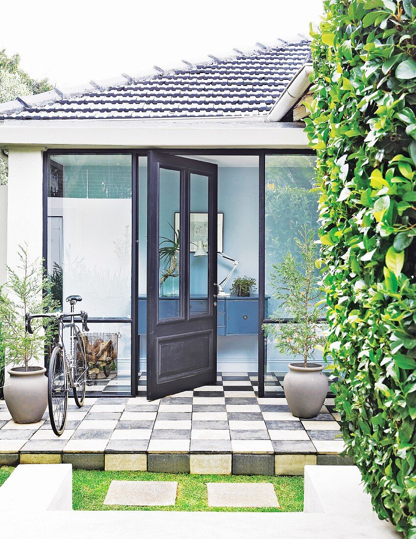 Open front door in porch with glass walls and chequered floor