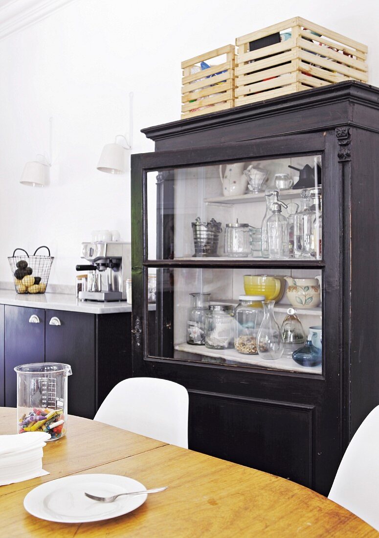 Black glass-fronted cabinet behind dining area in kitchen