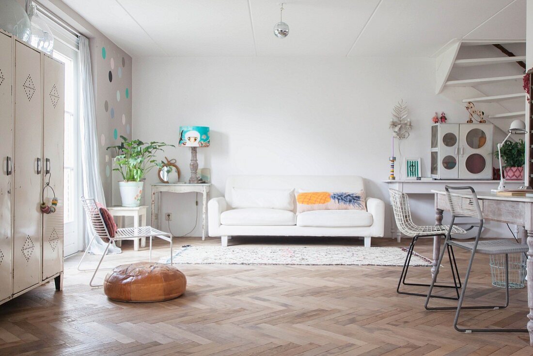 Herringbone parquet floor and white couch next to shabby-chic table in open-plan interior