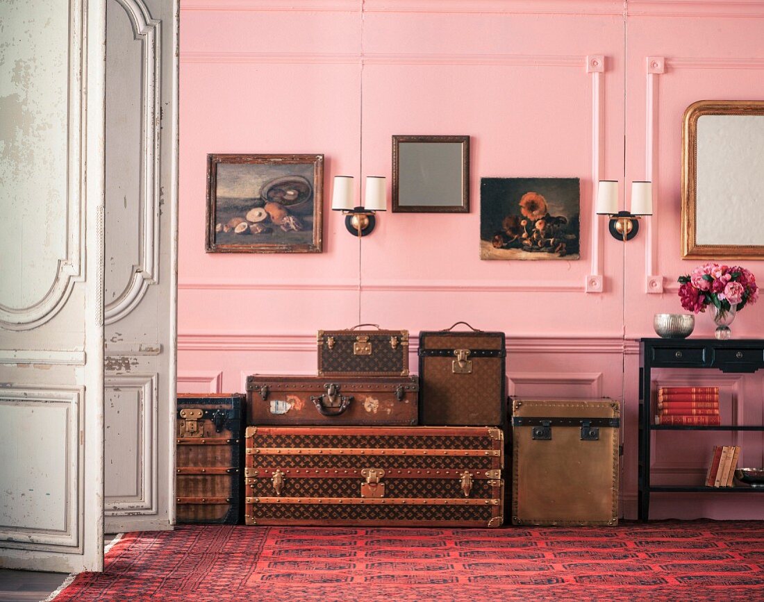 Antike Koffer vor rosafarberner Wandvertäfelung