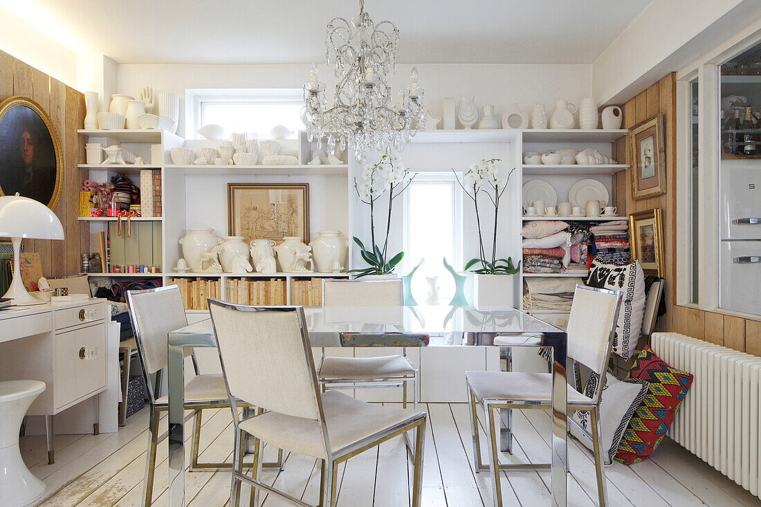 Dining table and chairs in front of collection of ceramics on shelves