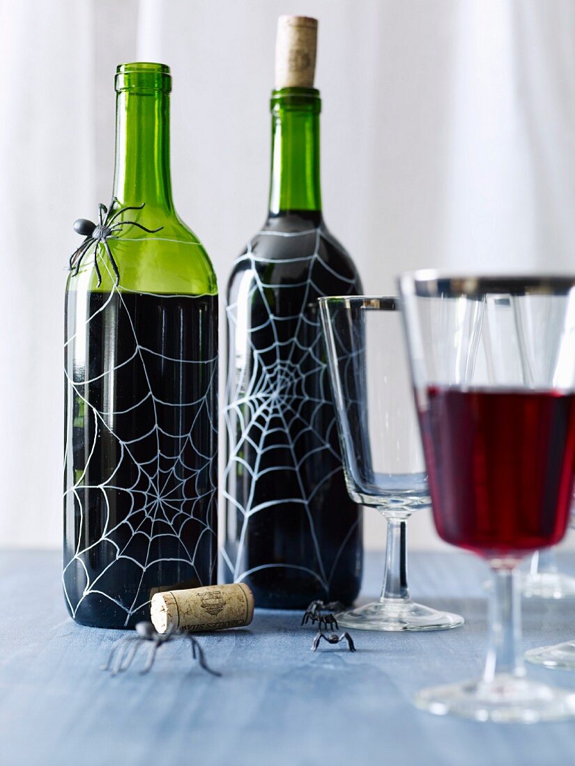 Weinflaschen gruselig dekoriert mit Spinnen und aufgemalten Spinnennetzen