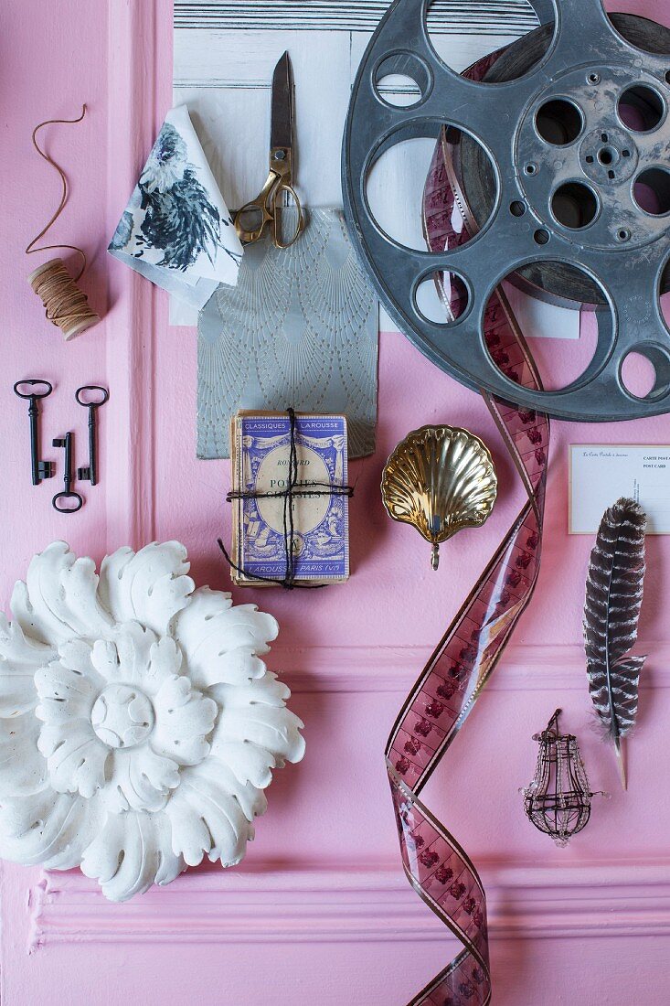 Mood board with film reel and knick-knacks on pink surface