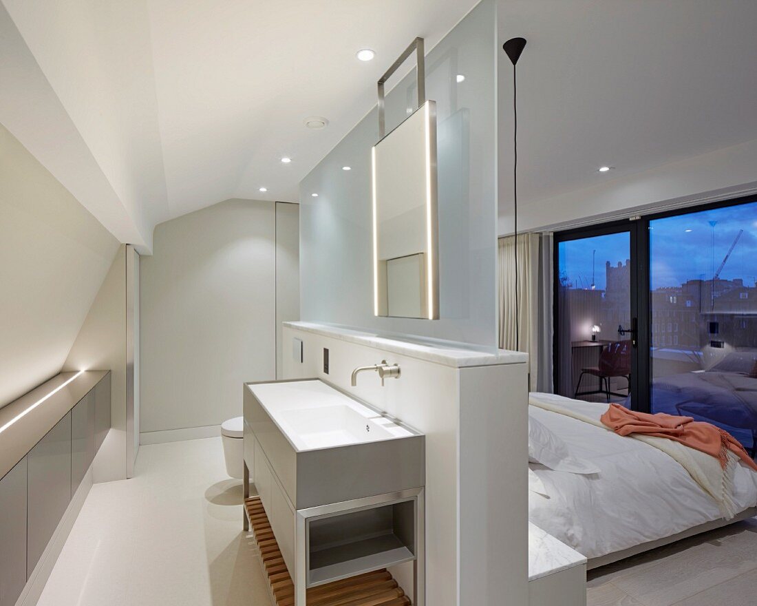 Moderner Schlafraum mit abgetrenntem Badbereich; Waschtisch an freistehender Brüstungswand mit Glasscheibe vor Doppelbett