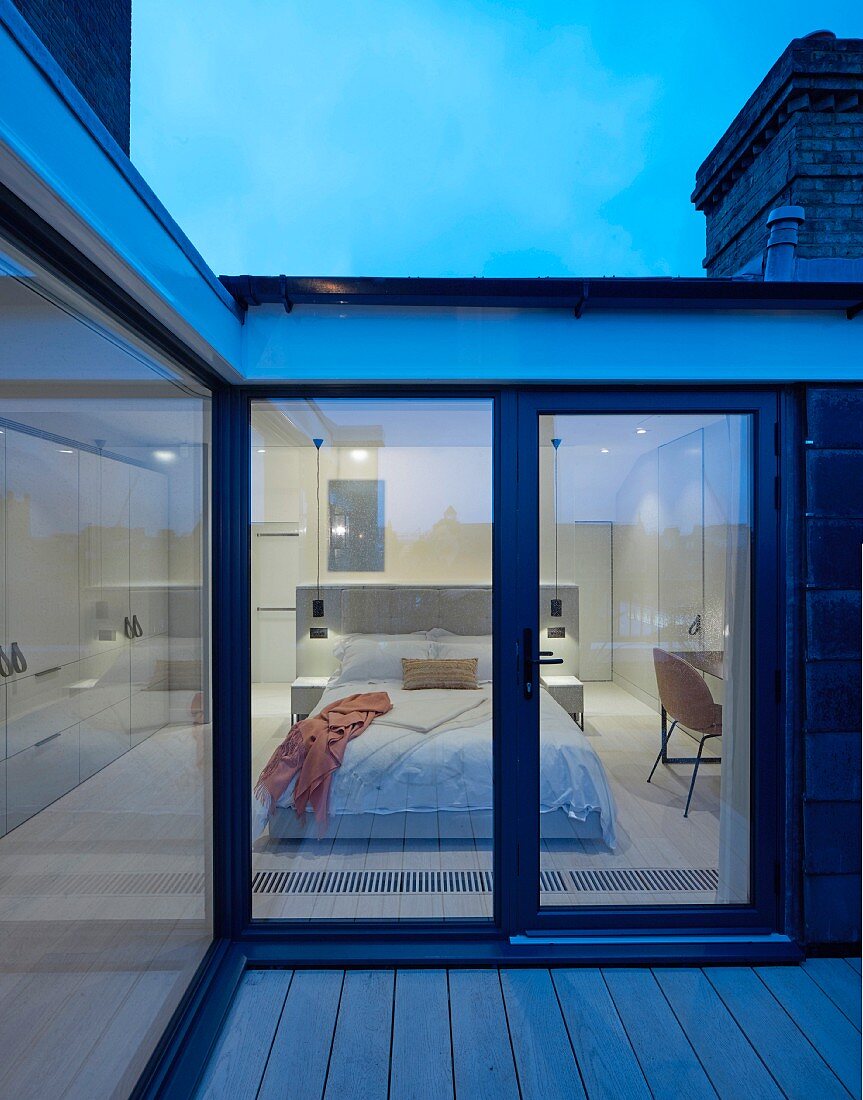 Dämmerstimmung über Dachterrasse mit Blick in modernes, elegantes Schlafzimmer