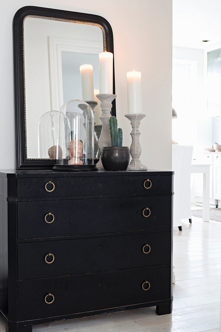 Mirror and ornaments on black chest of drawers