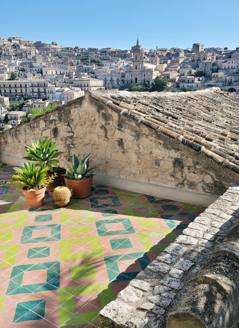 Mediterrane Dachterrasse mit geometrischem Fliesenmuster und Stadtblick