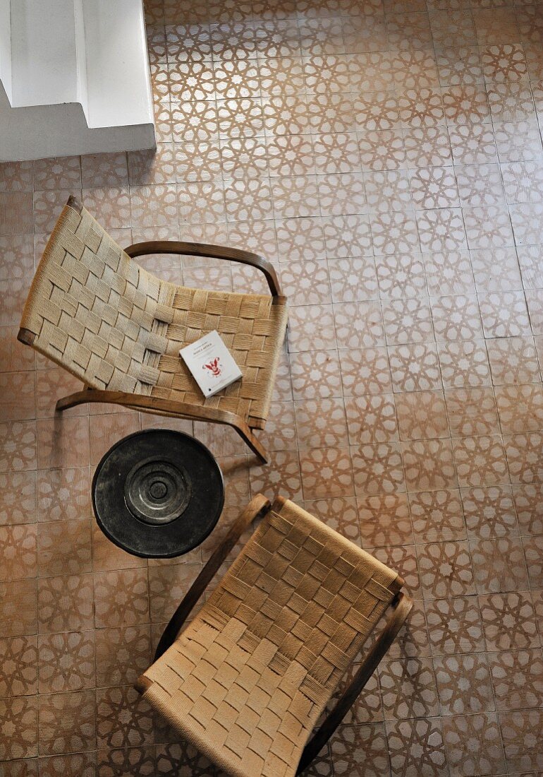 Zwei Retro Armlehnstühle mit geflochtener Sitzfläche auf Fliesenboden