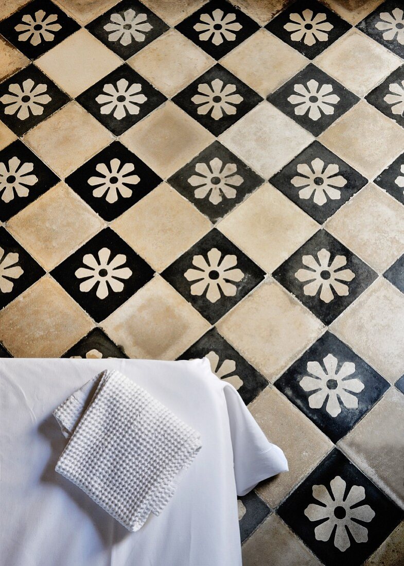 Traditional chequered tiled floor with white flowers on black tiles