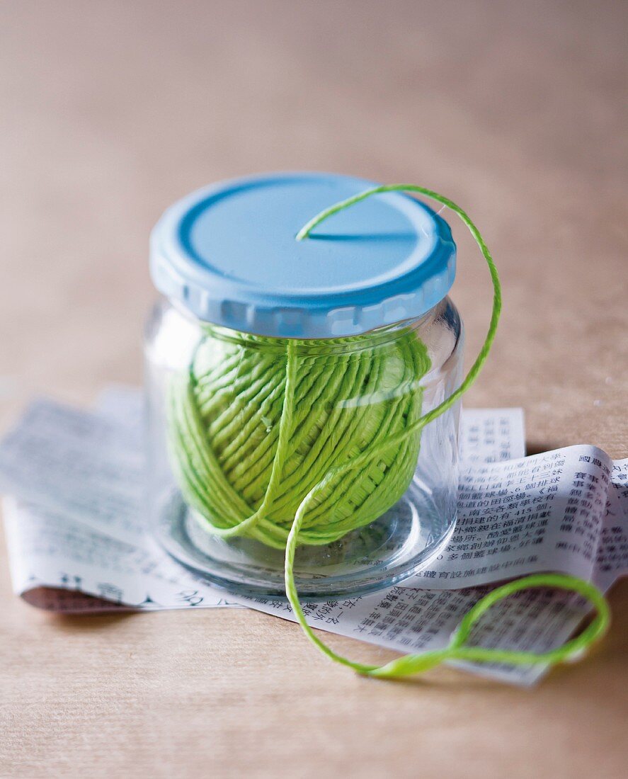 Green yarn in screw-top jar with hole in lid