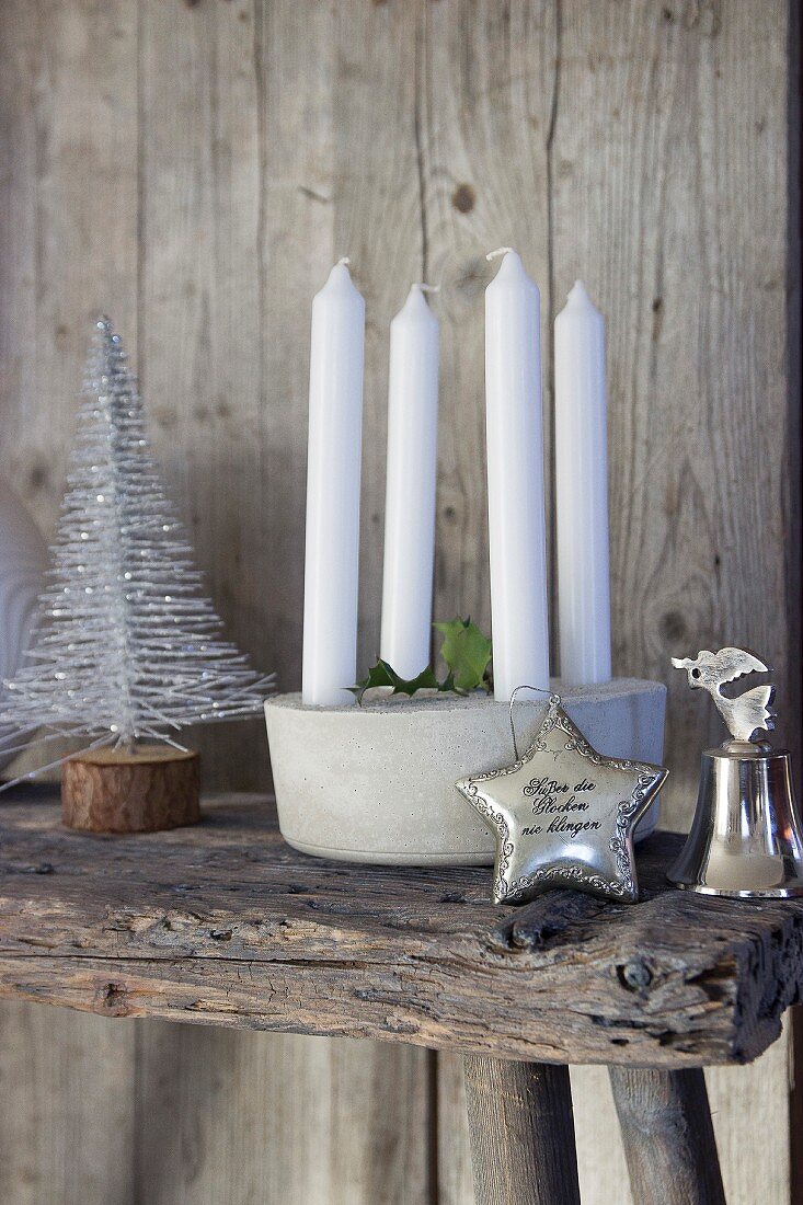 Kerzendekoration, stilisiertes Weihnachtsbäumchen, Silberstern und Silberglocke auf Holzunterlage