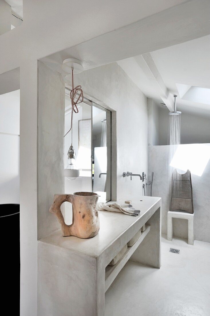 Concrete washstand with wall-mounted taps in front of shower area