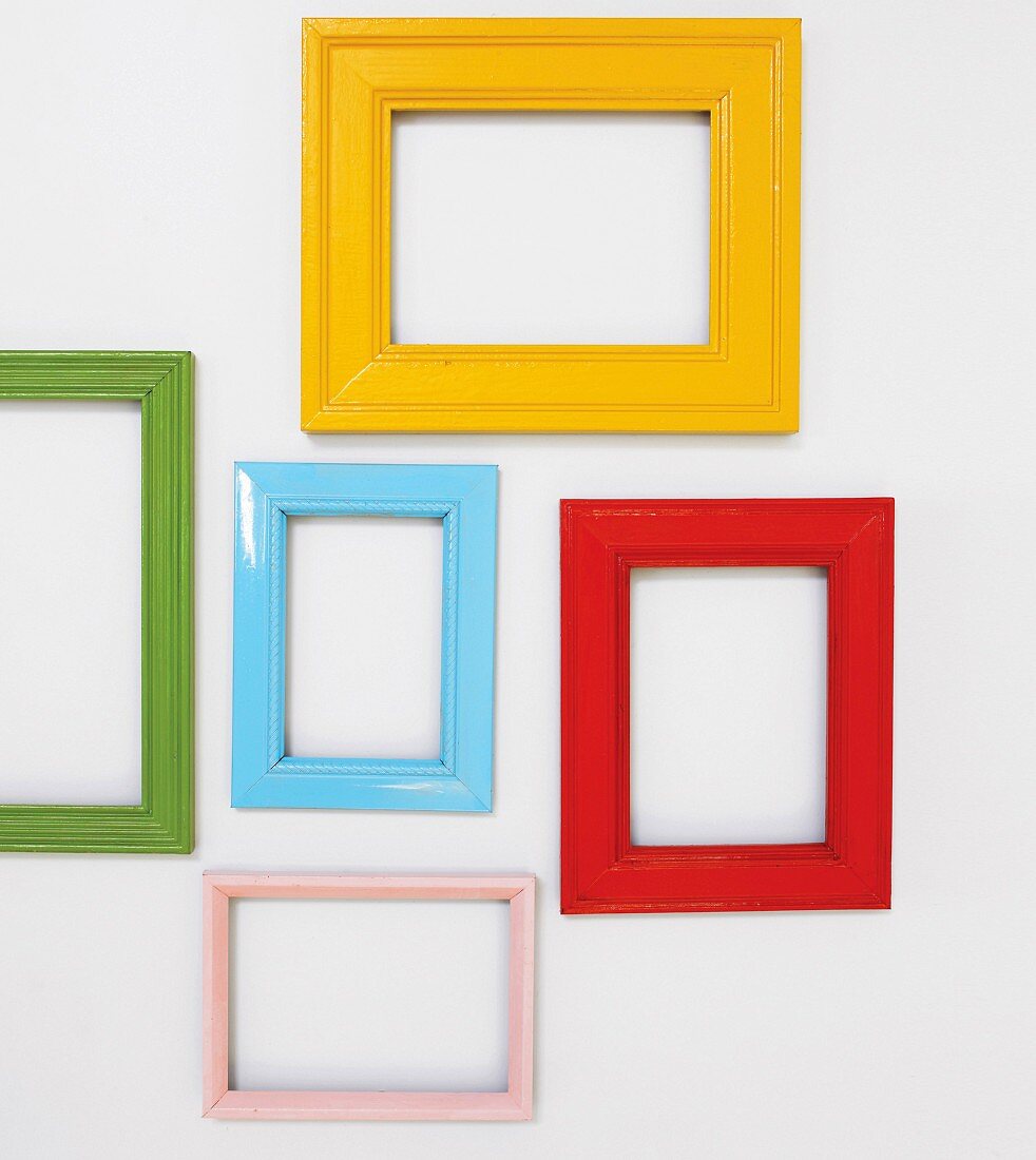 Picture frames painted various colours hung on white wall