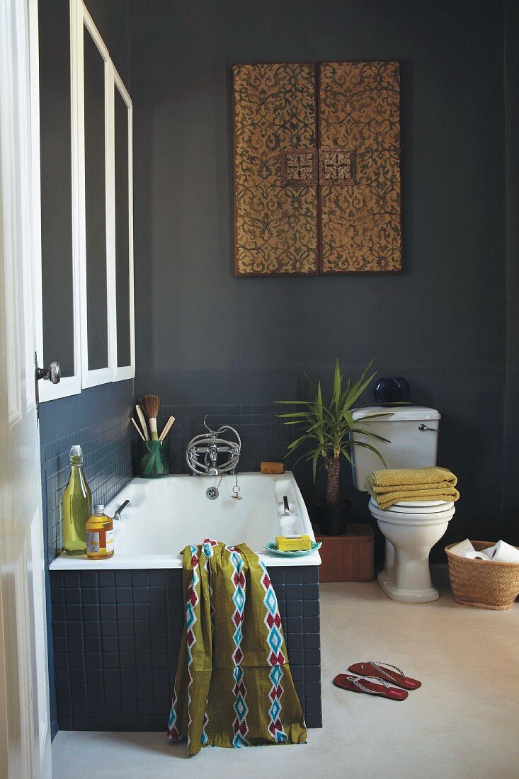 Ethnic bathroom with dark blue wall tiles below walls painted in matching blue