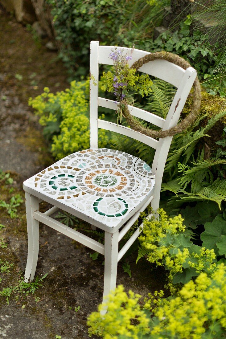 Stuhl mit Mosaik auf der Sitzfläche im Garten