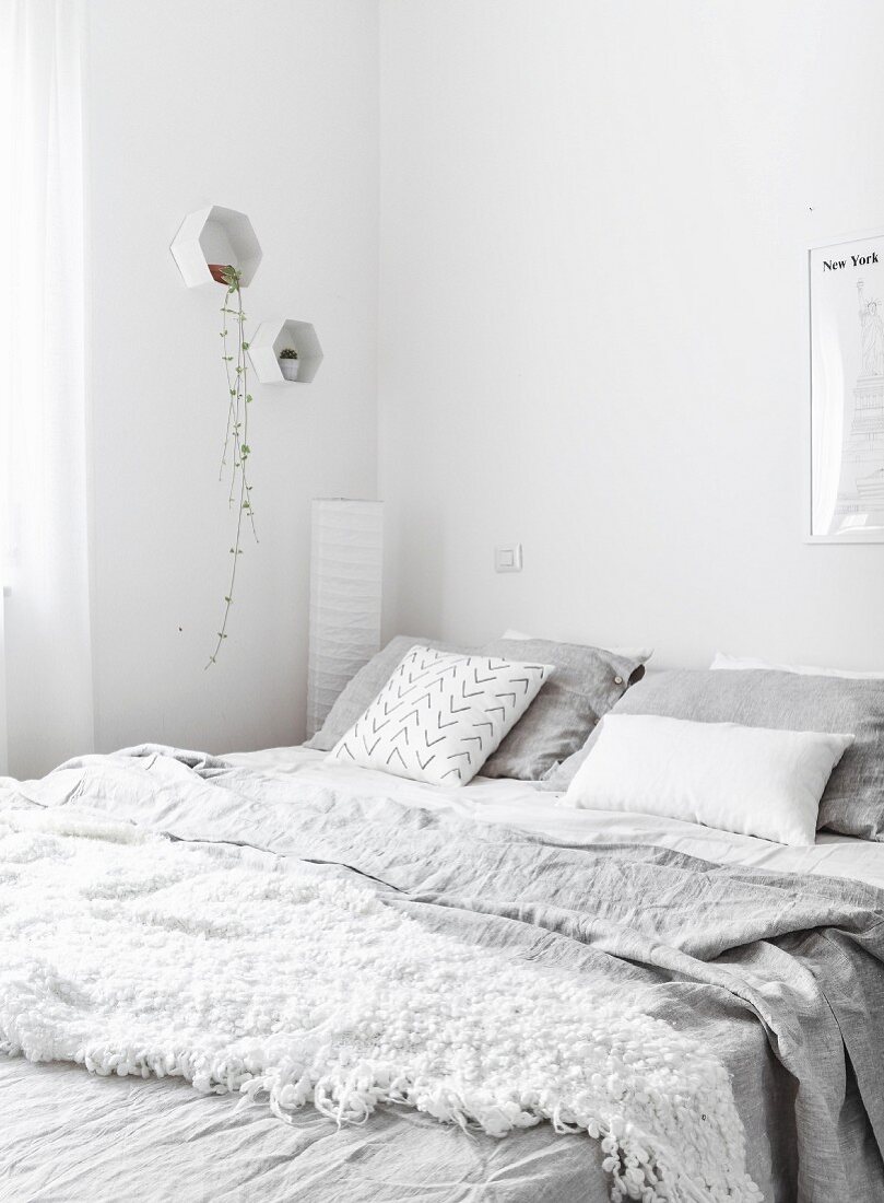 Weißes Schlafzimmer mit zerknitterter hellgrauer Bettwäsche