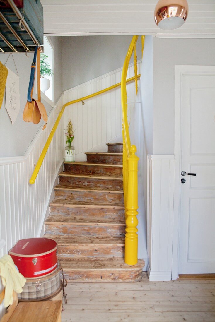 Rustic wooden staircase with yellow handrail and newel post in renovated period building