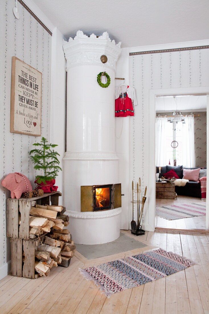 Weißer, kunsthandwerklicher Schwedenofen mit Kaminfeuer in weihnachtlichem, skandinavischem Ambiente