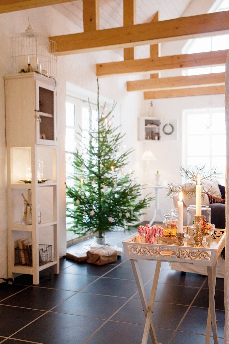 Carved tray table, lit candles and sweets in front of Christmas tree