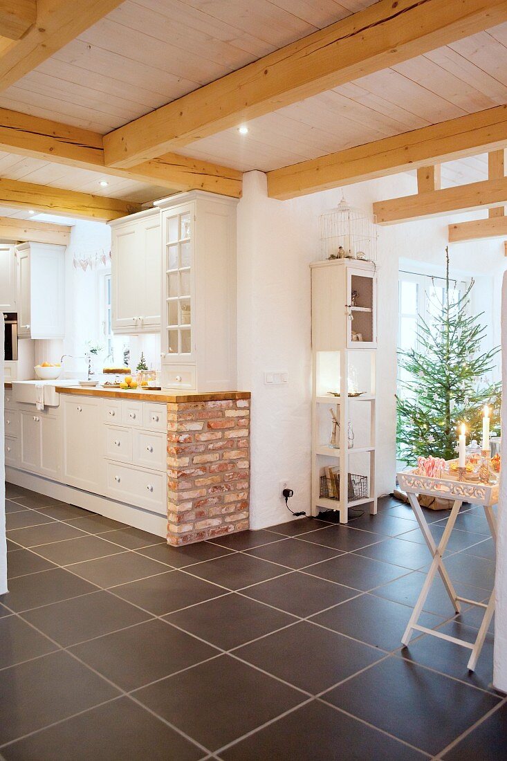 Landhausküche mit gemauertem Abschluss vor offenem Wohnbereich mit Weihnachtsbaum