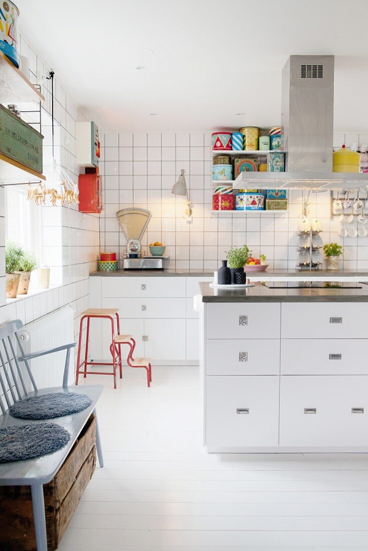 weiße Einbauküche mit Retro Küchenwaage, bunten Blechdosen und Kücheninsel