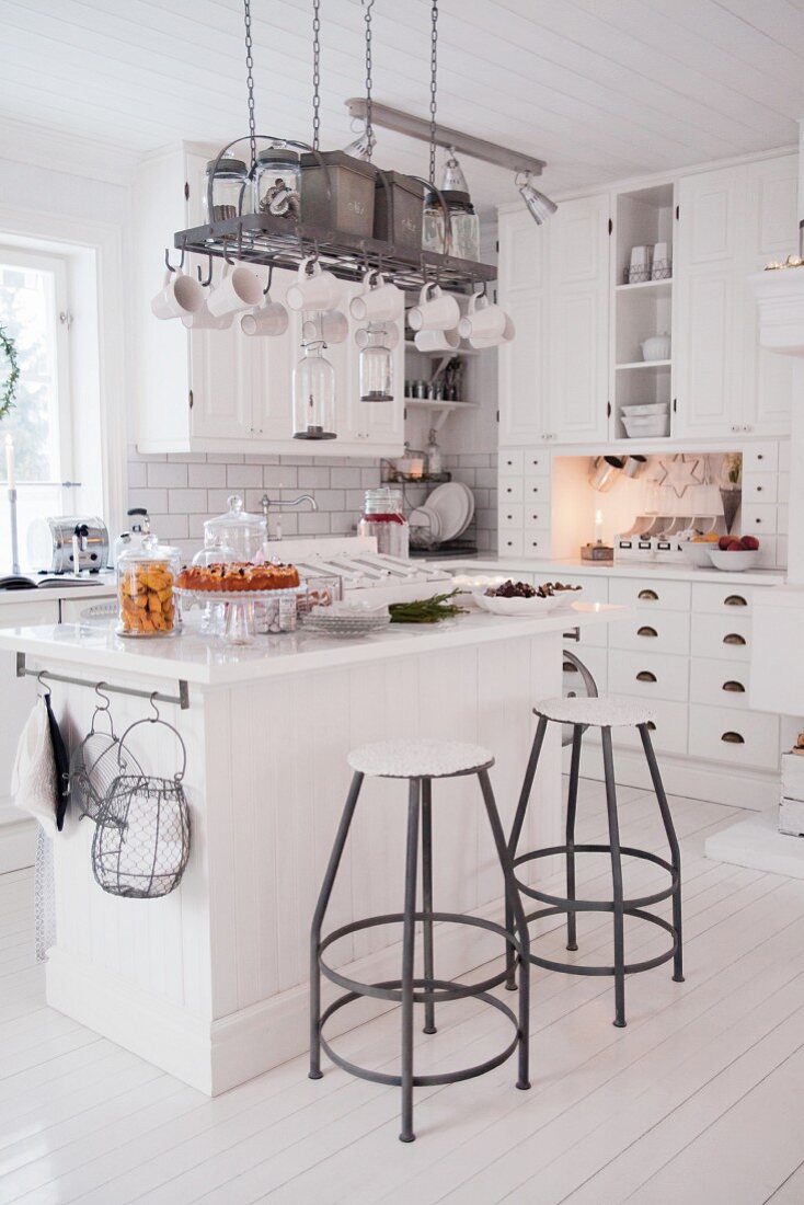 Island counter and bar stools in white country-house kitchen