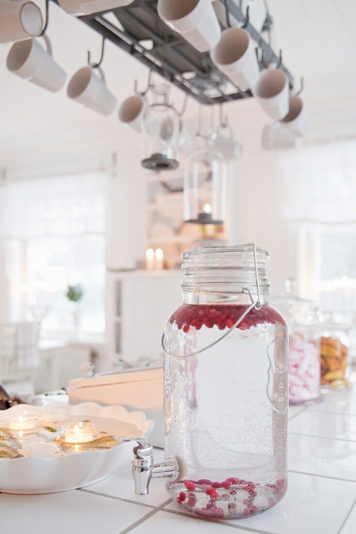 Water and berries in vintage-style drinks dispenser in kitchen