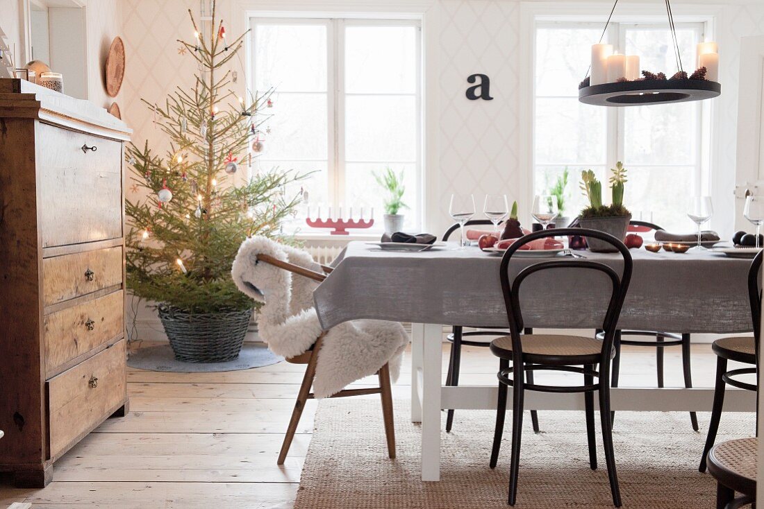 Gedeckter Tisch mit Kaffeehausstühlen und Weihnachtsbaum