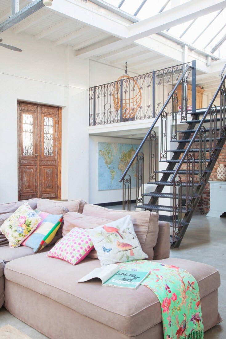 Antique front door, steel stairs leading to gallery and comfortable sofa in loft apartment