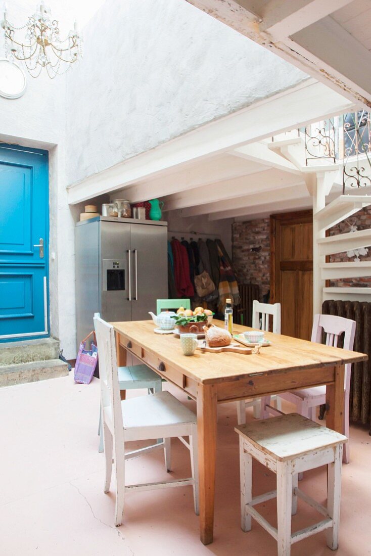 Dining table, vintage chairs and blue panelled door in loft apartment