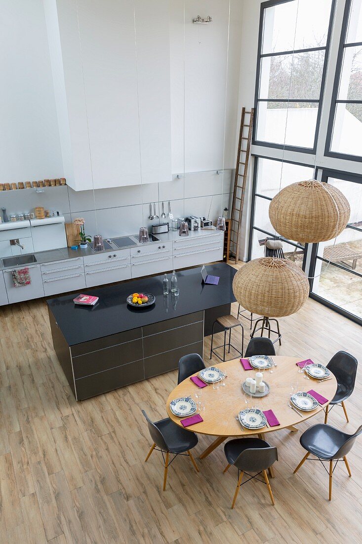 Blick auf offene Küche mit ovalem, gedecktem Esstisch in Loftwohnung