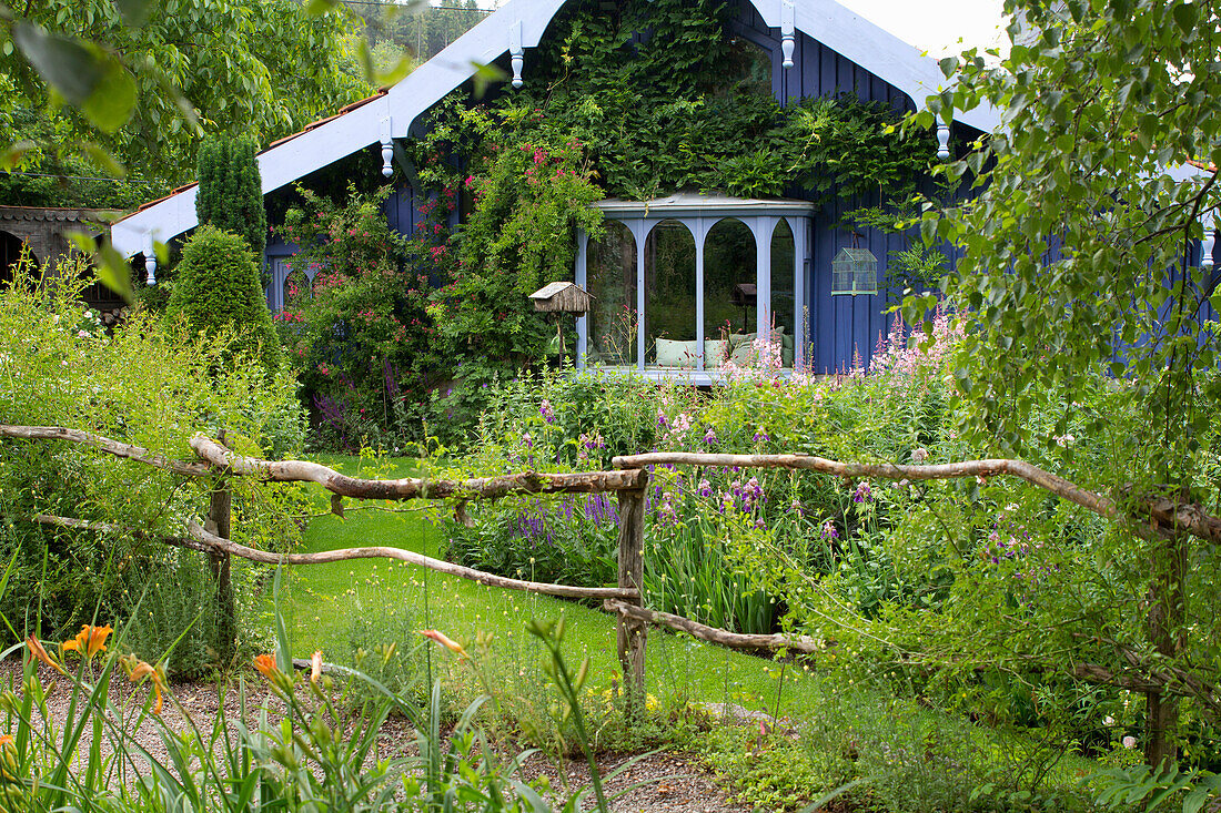 Idyllischer Garten mit naturnahem Zaun und ländlichem Haus