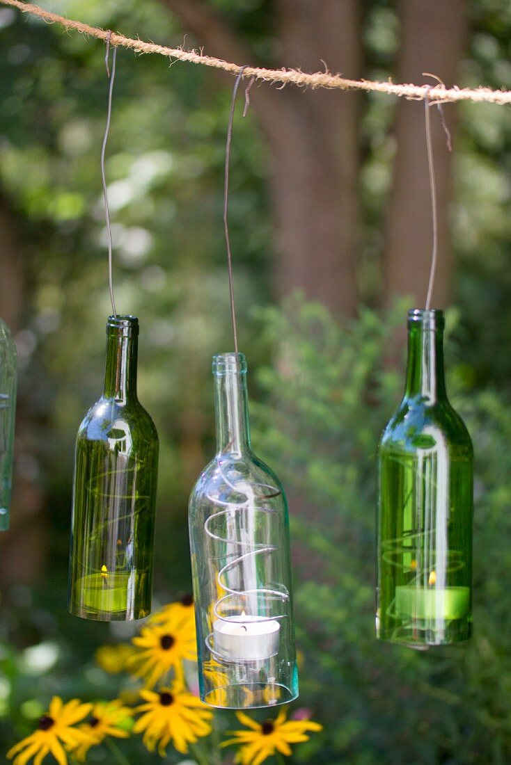 Glasflaschen mit Teelichtern an rustikalem Seil aufgehängt