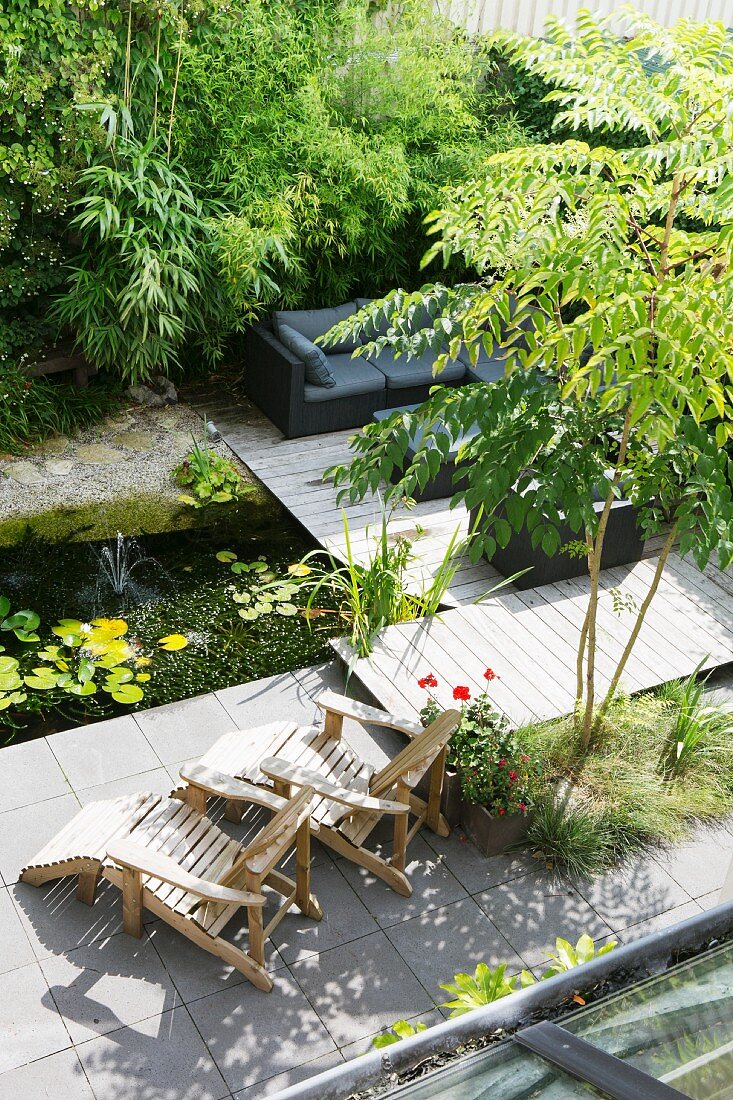 Gartenteich, Holzliegestühle und Lounge neben Bambus auf Holzterrasse