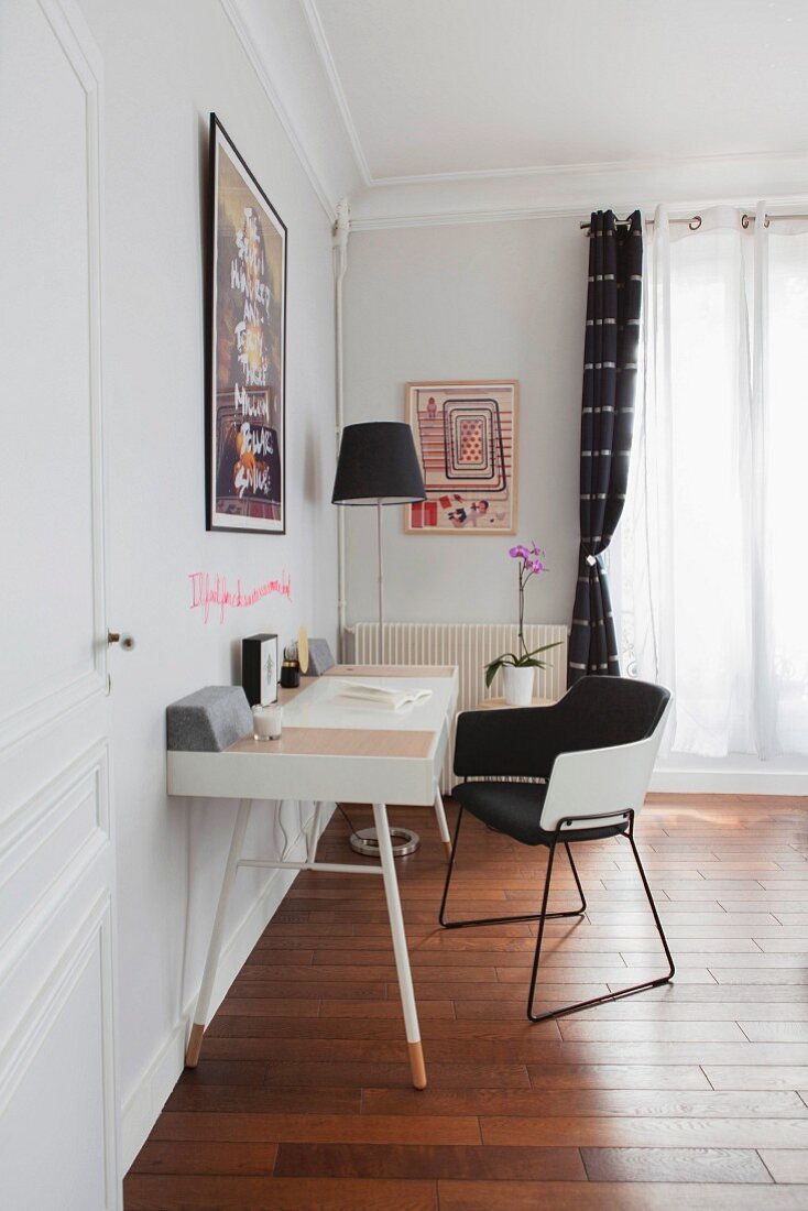 Schreibtisch mit schwarz-weißem Armlehnstuhl vor Fenster