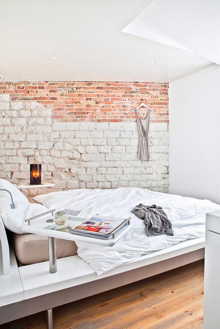 Designer bed and exposed stone and brick wall in bright bedroom