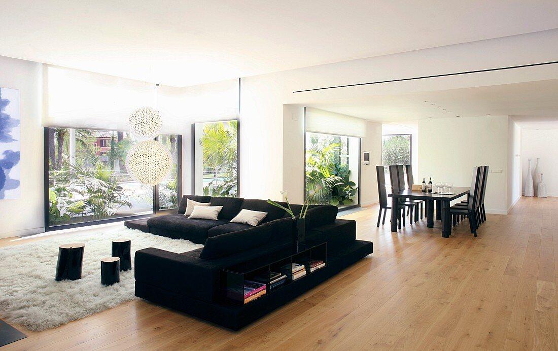 Moderner offener Wohnraum mit Esstisch und Sofa in Schwarz