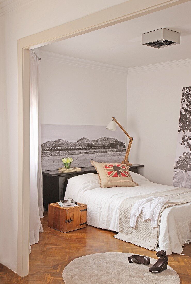Blick in Schlafzimmer mit schwarz-weißen Fotoaufnahmen und Bett mit Dekokissen
