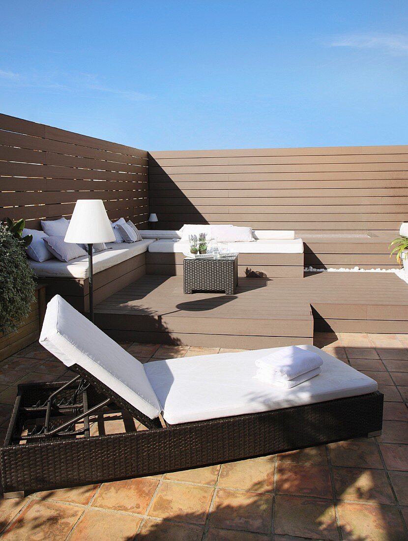 Elegant lounger and benches with cushions on sunny roof terrace