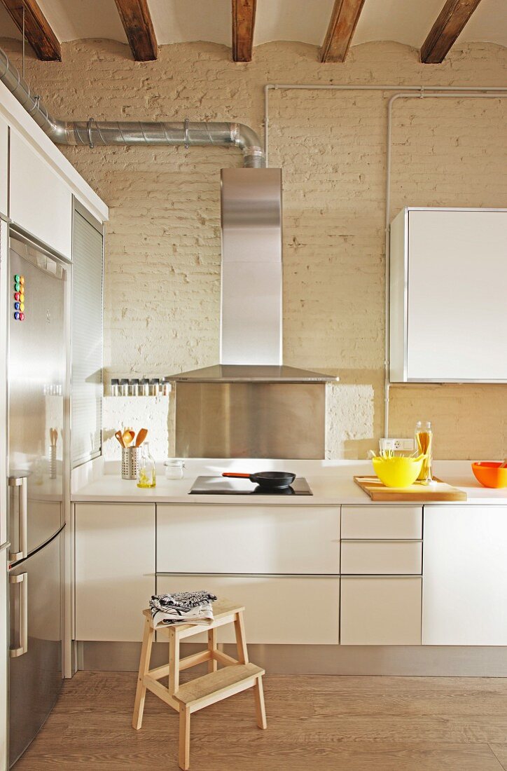 weiße Küchenzeile mit Dunstabzugshaube in hohem Raum mit Loftcharakter