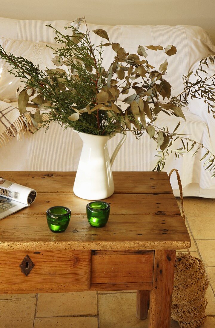 Kanne mit Zweigen auf einem Holztisch im Wohnzimmer