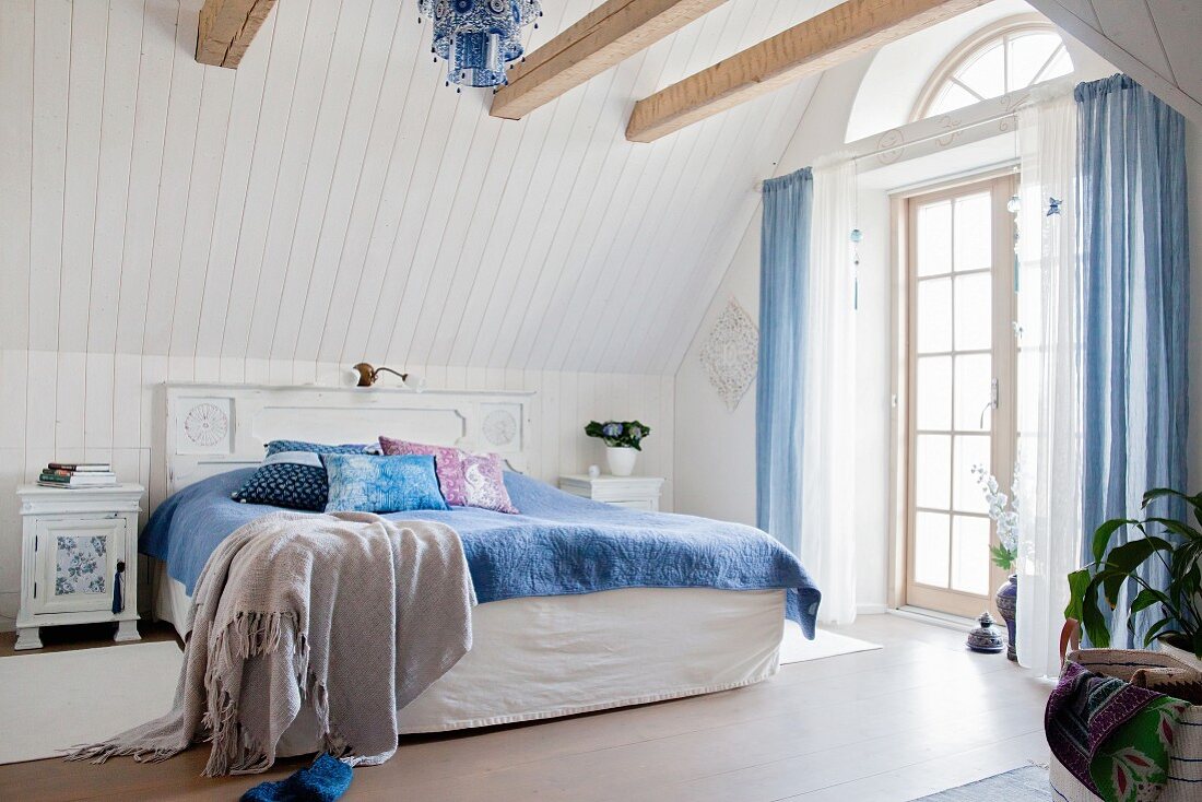 Exposed wooden beams in vintage-style country-house bedroom
