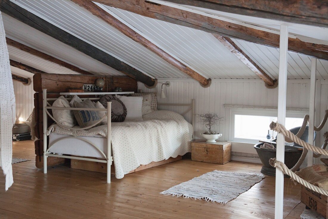 Niedriger Raum unter dem Dach in Naturtönen mit einem Tagesbett
