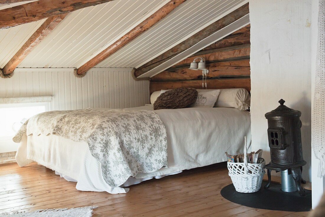 Rustikales Schlafzimmer unter dem Dach mit Holzbalken und Ofen
