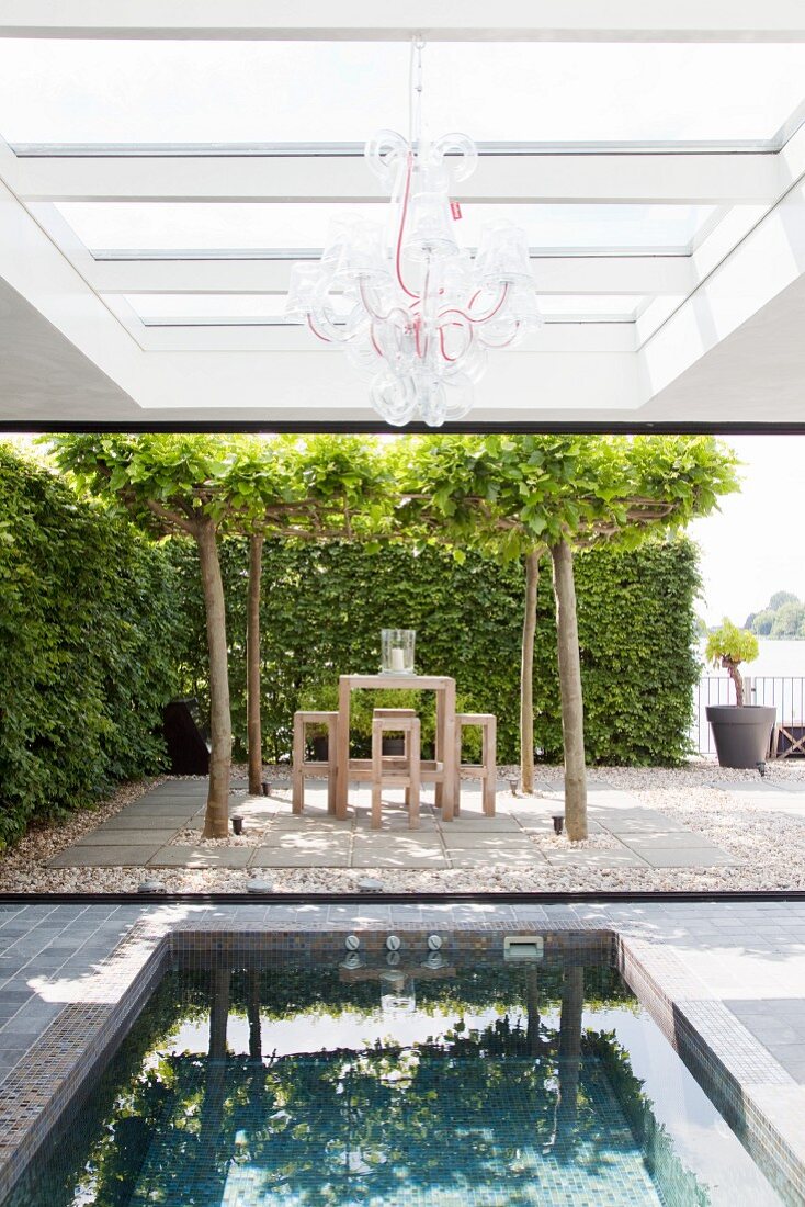 Roofed outdoor pool and terrace below canopy of trees