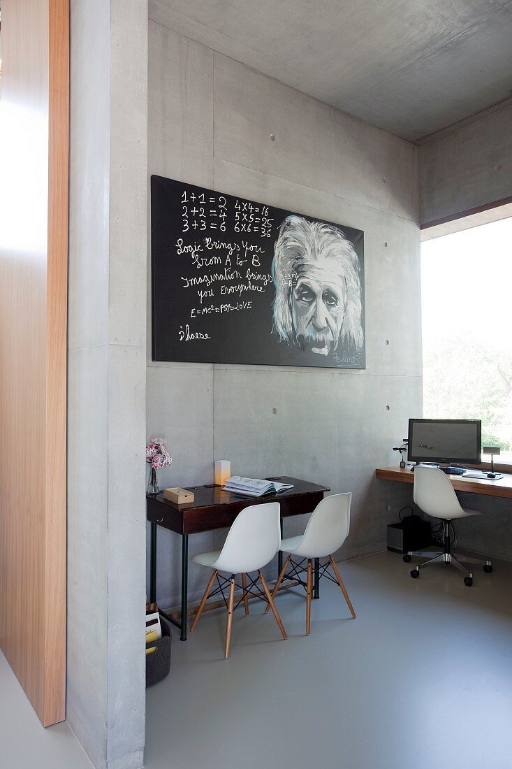White classic chairs and picture of Albert Einstein in study in concrete house