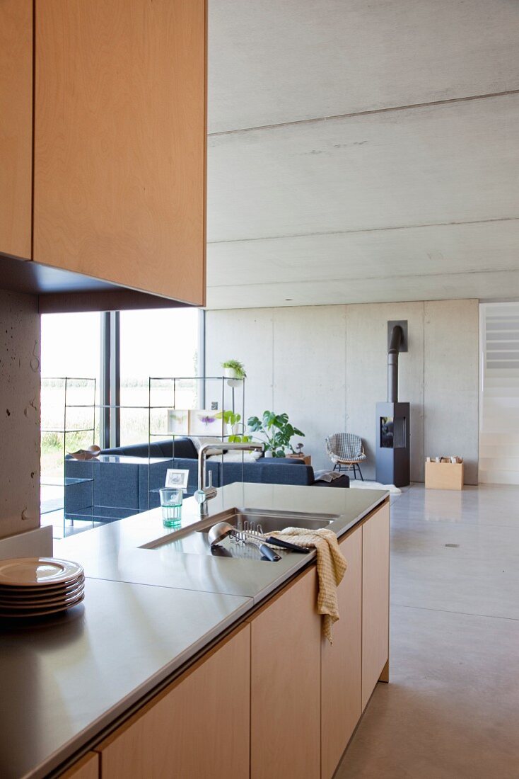 Küchenzeile mit Spülbecken in offenem Wohnraum, im Hintergrund Lounge mit Sofa und Kamin