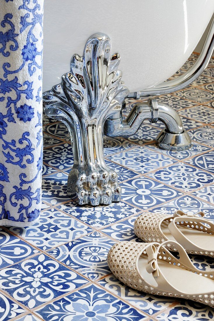 Claw foot of bathtub on blue and white patterned floor tiles