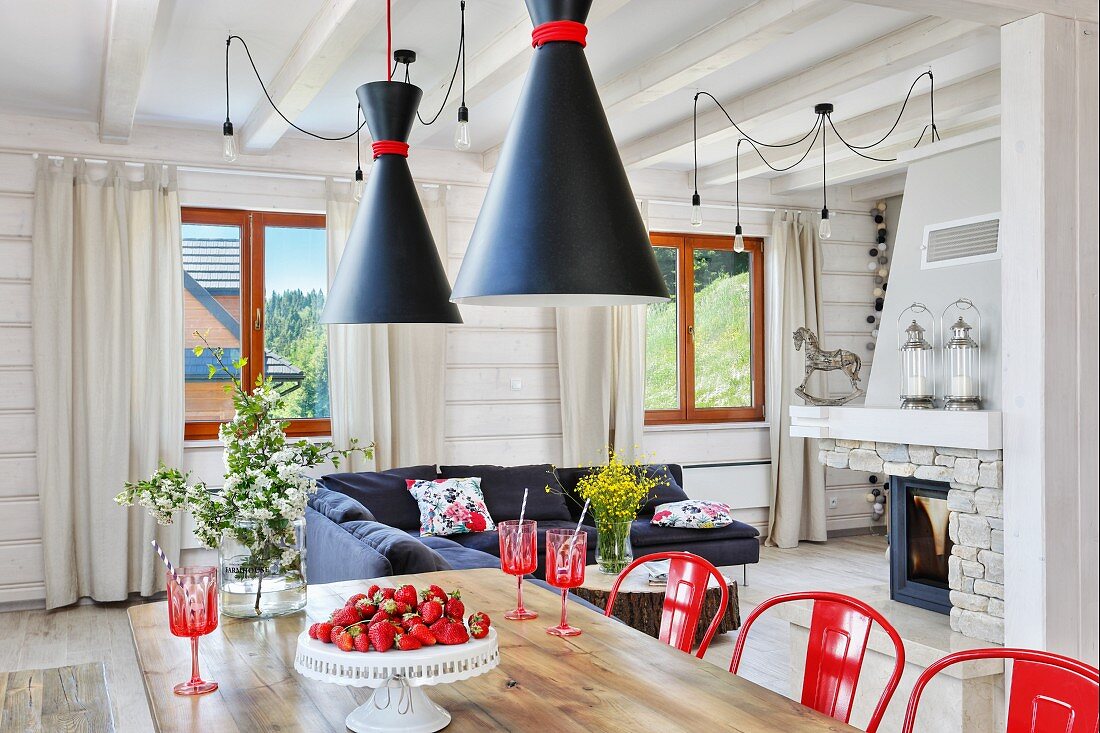 Offener Wohnraum mit roten Farbakzenten im weißen Holzhaus